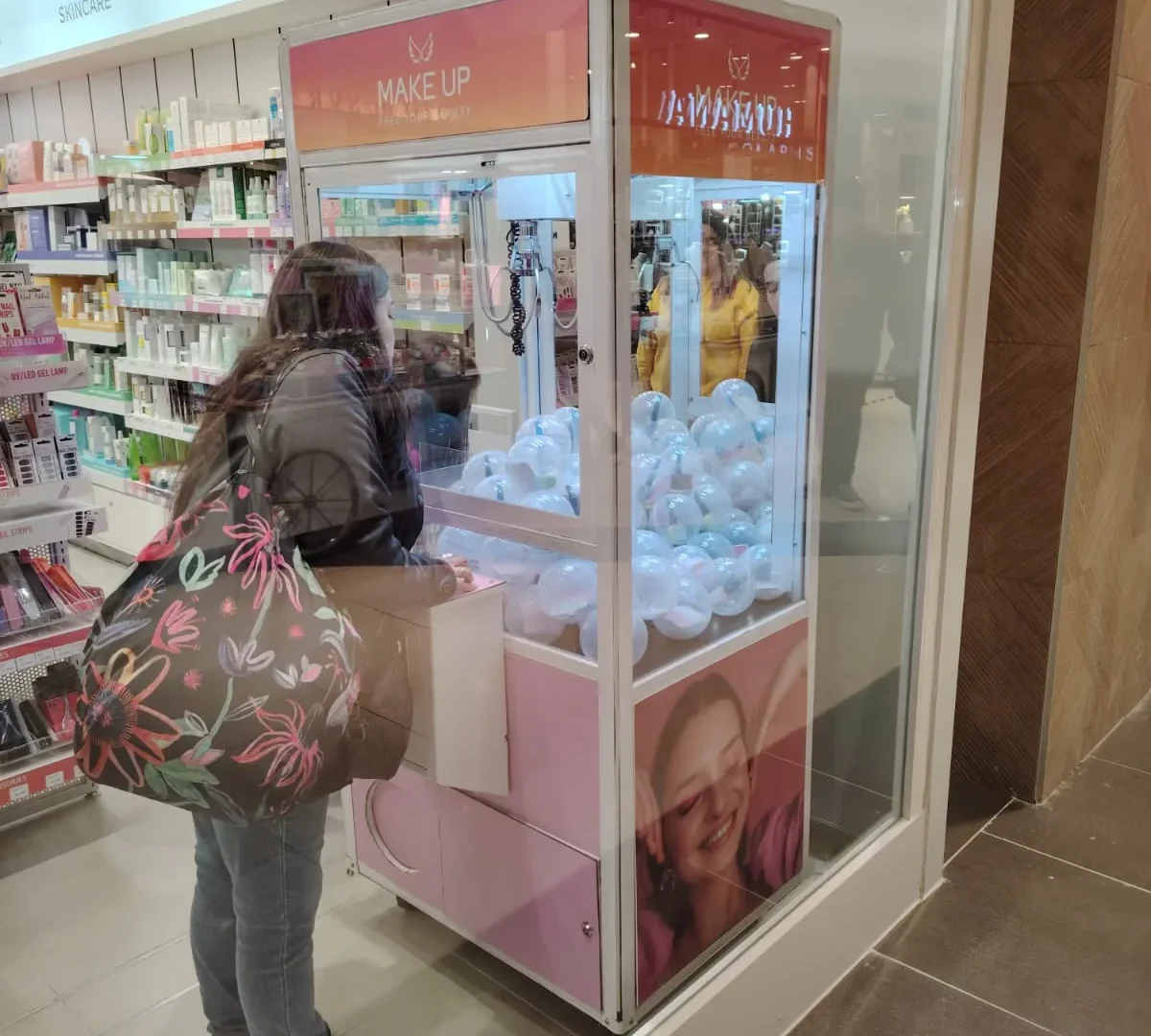 Clienta jugando en una peluchera personalizada instalada dentro de una tienda de maquillaje